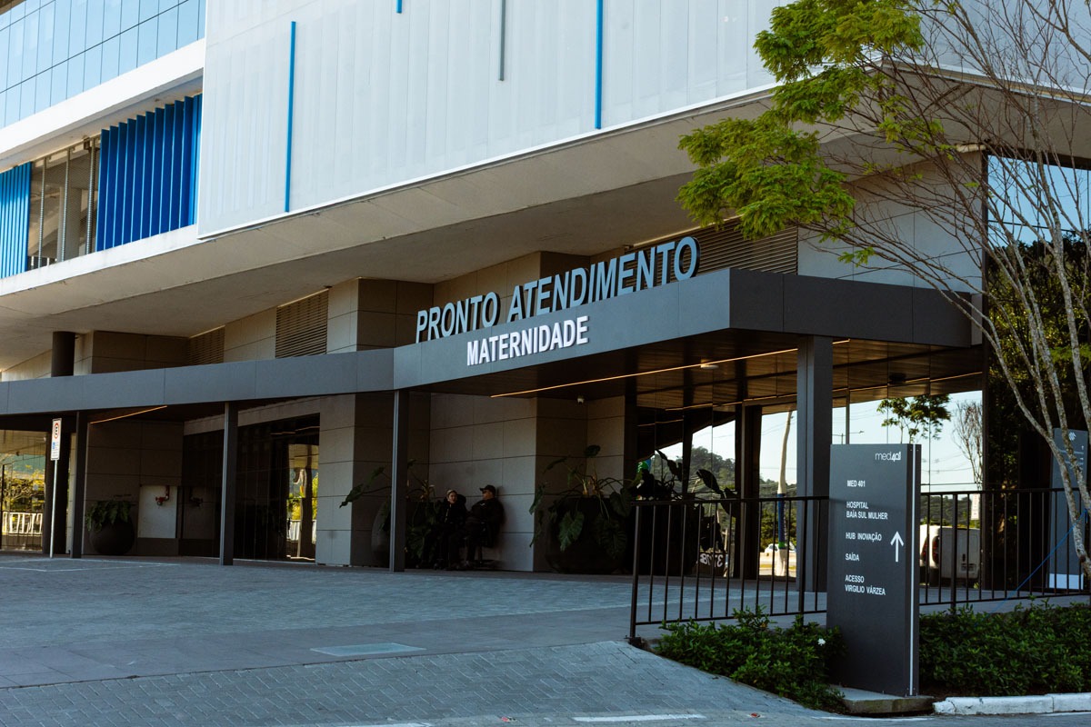 Fotografia da entrada do pronto atendimento maternidade, com placa de orientação e fachada moderna.
