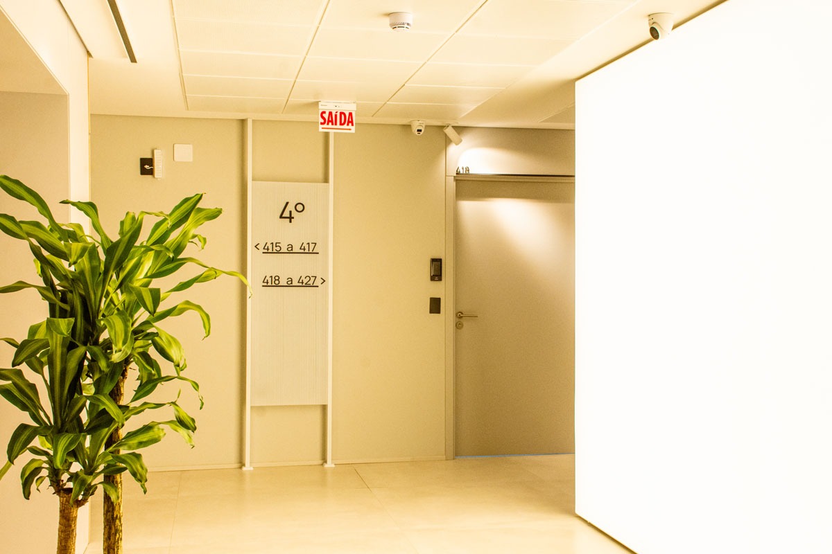 Fotografia de corredor do quarto andar, com placa de saída, planta e sinalização para salas quatrocentos e quinze a quatrocentos e vinte e sete.