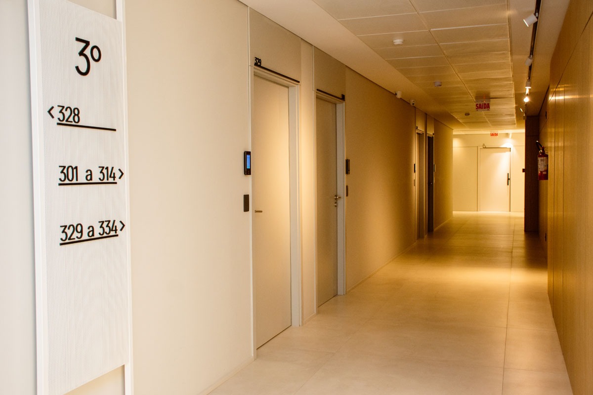 Fotografia de corredor do terceiro andar, com portas, placa de orientação e sinalização para salas trezentos e um a trezentos e trinta e quatro.